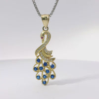 14KT Gold Charm Peacock with Blue CZ Stones Tail, White CZ Stones Body, Dark Pink CZ Stone Eye and Plain Bell